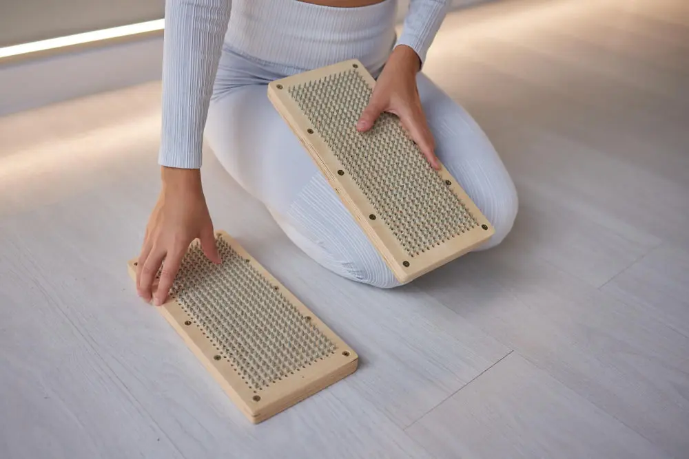 A person holding two rectangular wooden foot massage boards.