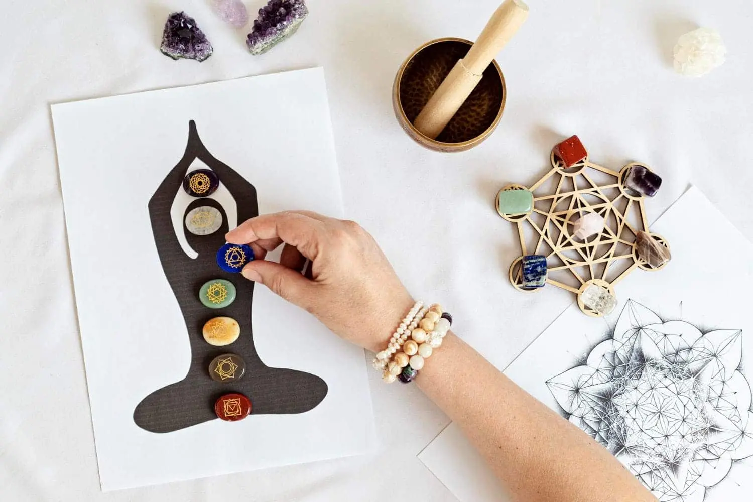 Hand placing chakra stone on a chakra diagram