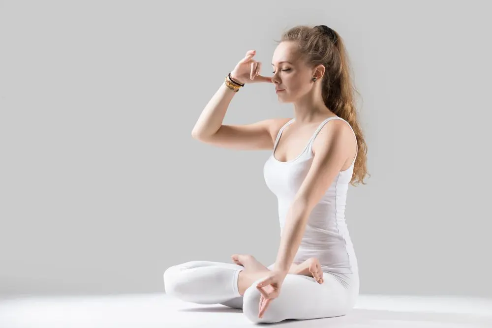 Woman practicing pranayama breathing exercise sitting cross-legged