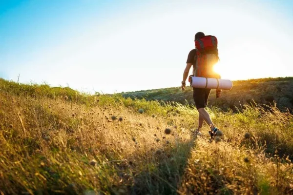 Hiker with backpack walking at sunset