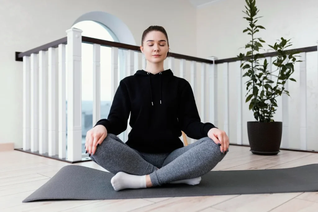 Woman in serene meditation posture on a yoga mat.