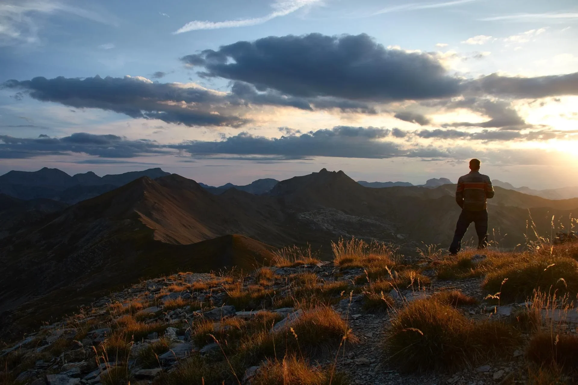 Man standing on a mountain peak at sunset