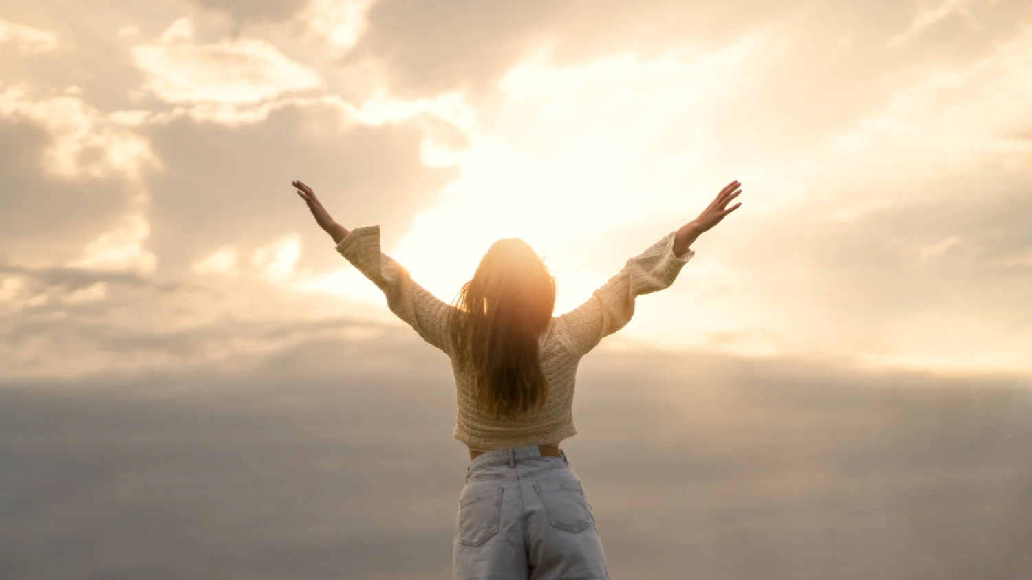 Woman with arms up enjoying sunset light