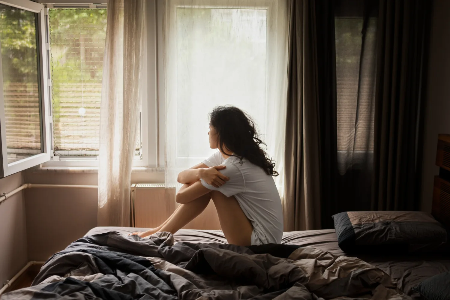 Young woman sitting alone and reflecting by a window