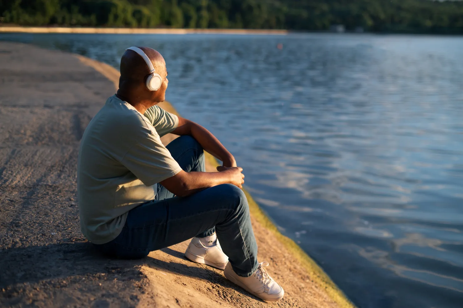 Man with headphones sitting peacefully by a lake